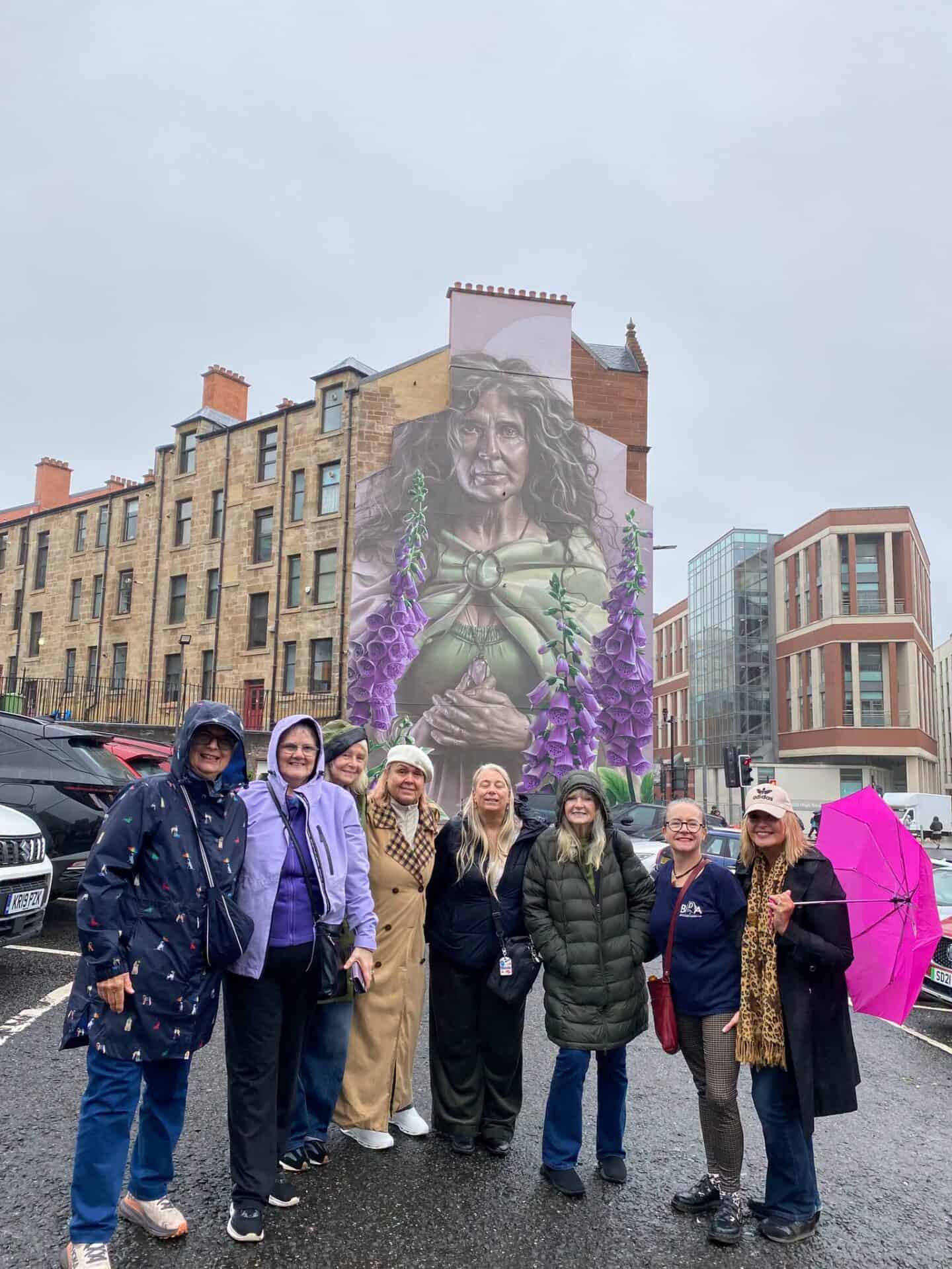 Group of people in front of a mural of a woman with BSL signs in Edinburgh.