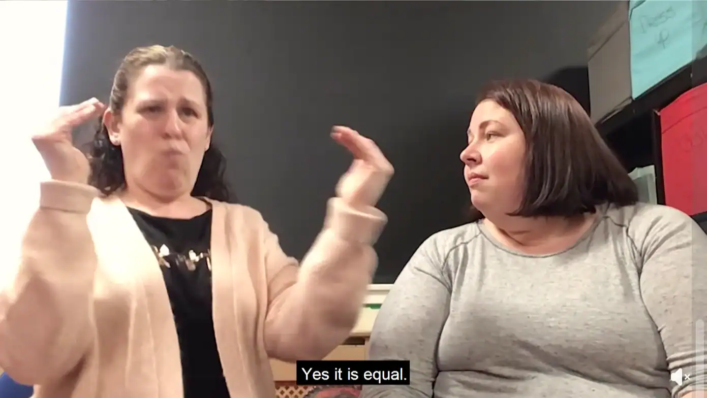 Deaf women engaging in a discussion about BSL Act 2015 in a classroom.