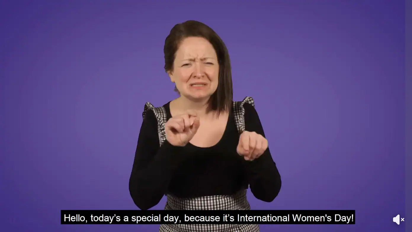 Deaf woman signing with a joyful expression for International Women's Day.